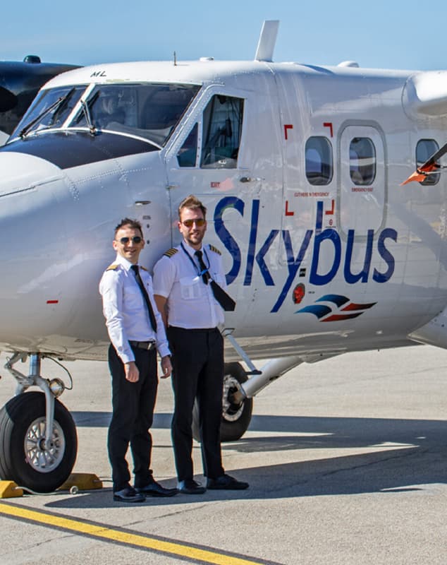 2 pilots standing in front of a Skybus twin otter at Cornwall Airport Newquay