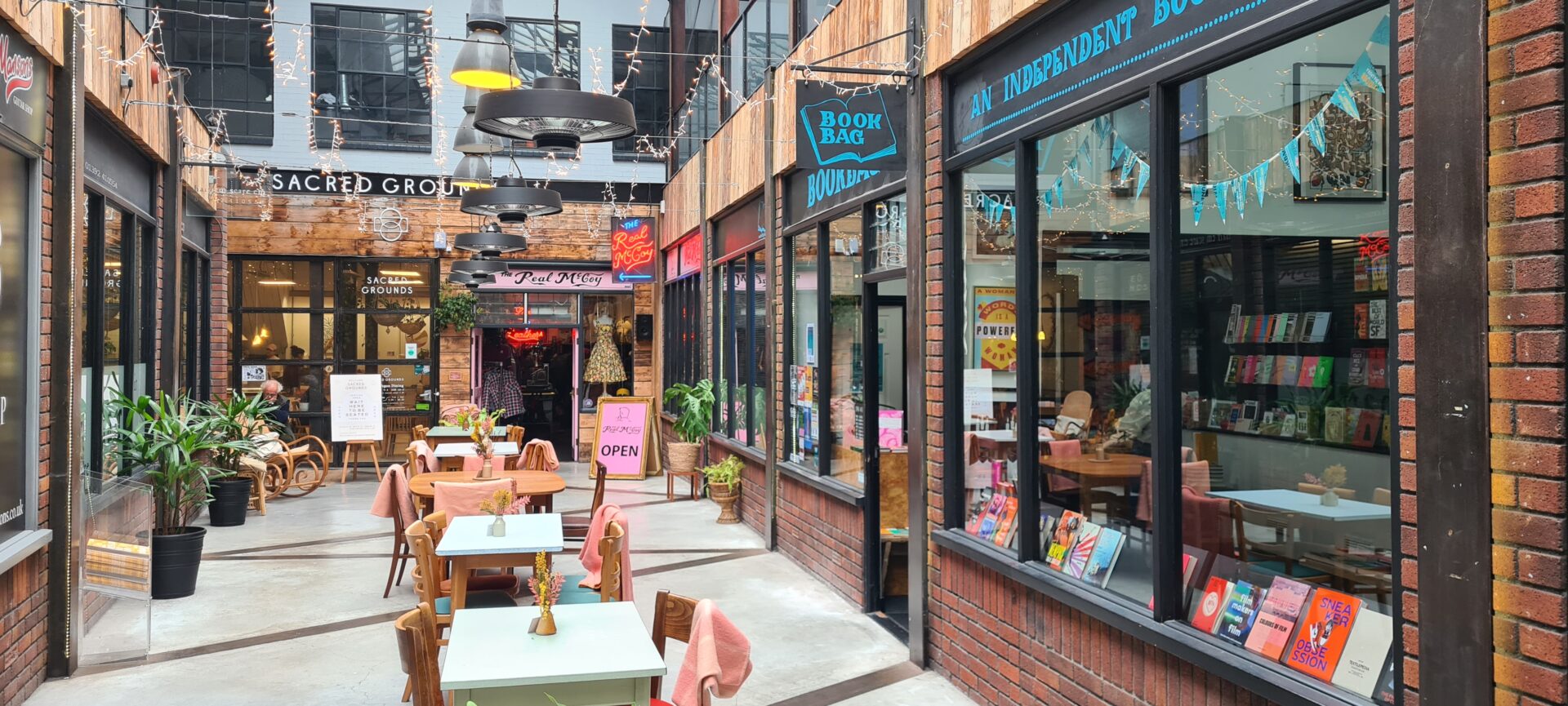 View down McCoy’s Arcade walkway lined with independent shops, cafes, and indoor seating.
