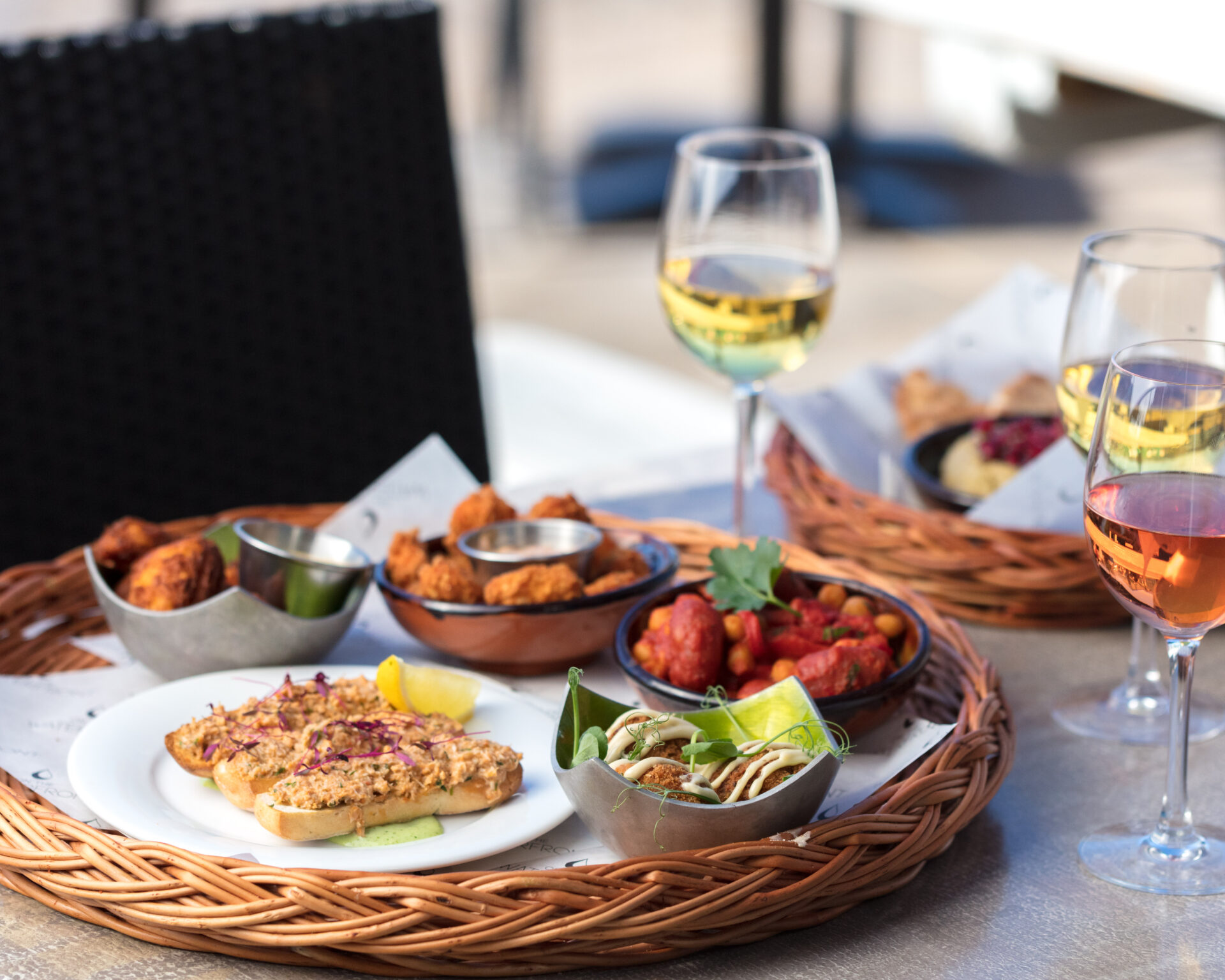 Close-up of small tapas dishes and a glass of wine served at an outdoor table in Exeter.