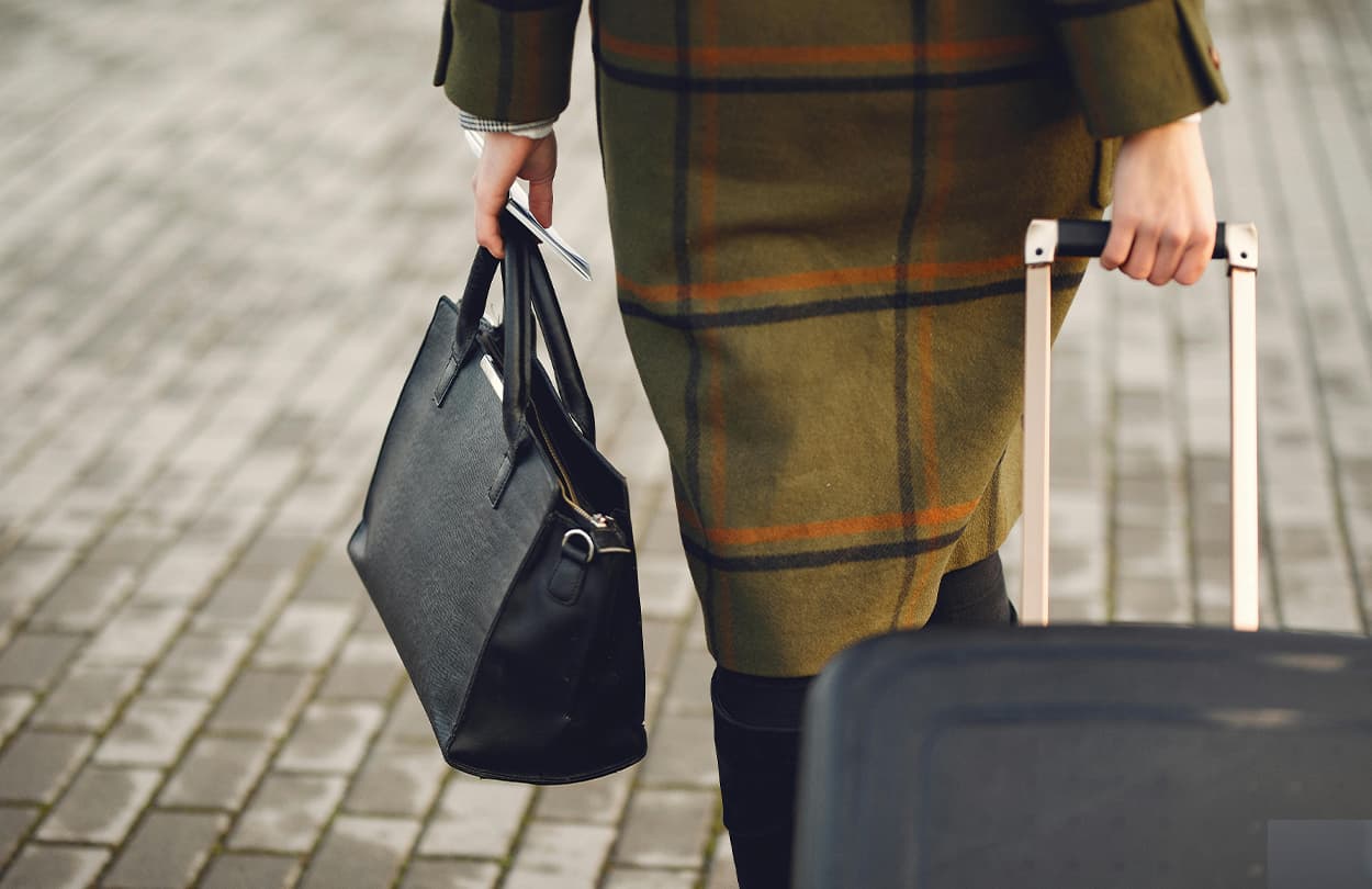 woman walking to the airport with her suitcase, handbag and travel documents