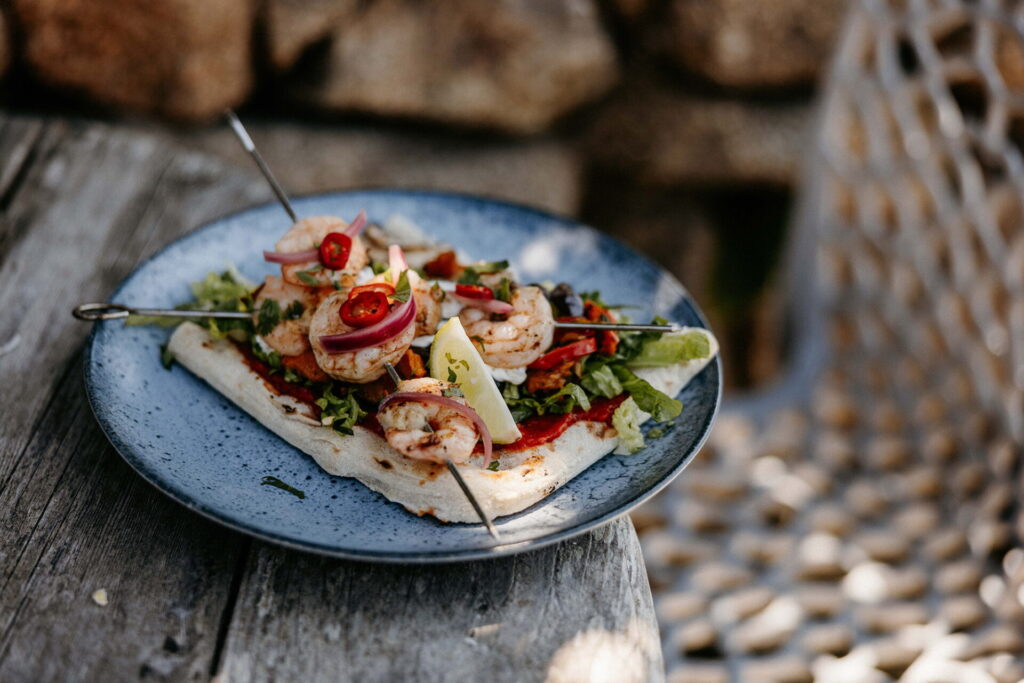 Flat bread with prawn skewers with fresh salad, lime and chilli on a plate